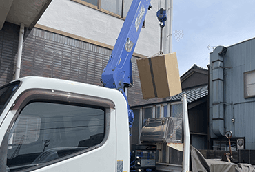 クレーンで金庫を積み込む運搬作業